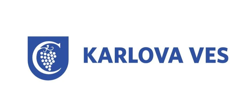 Modré logo s hroznom a štítom vedľa nápisu „KARLOVA VES“ na bielom pozadí.